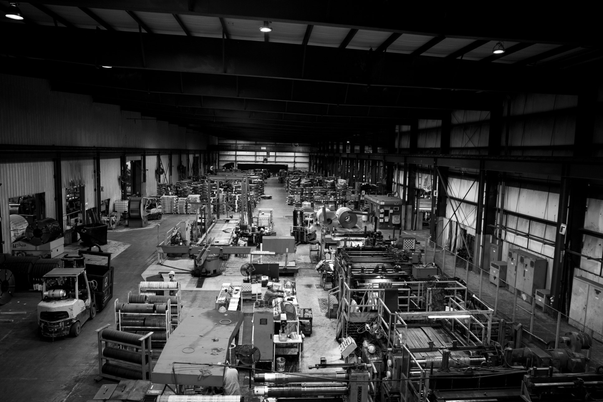 Black and white view of Heidtman Steel’s Butler facility with machinery, steel coils, and workers.
