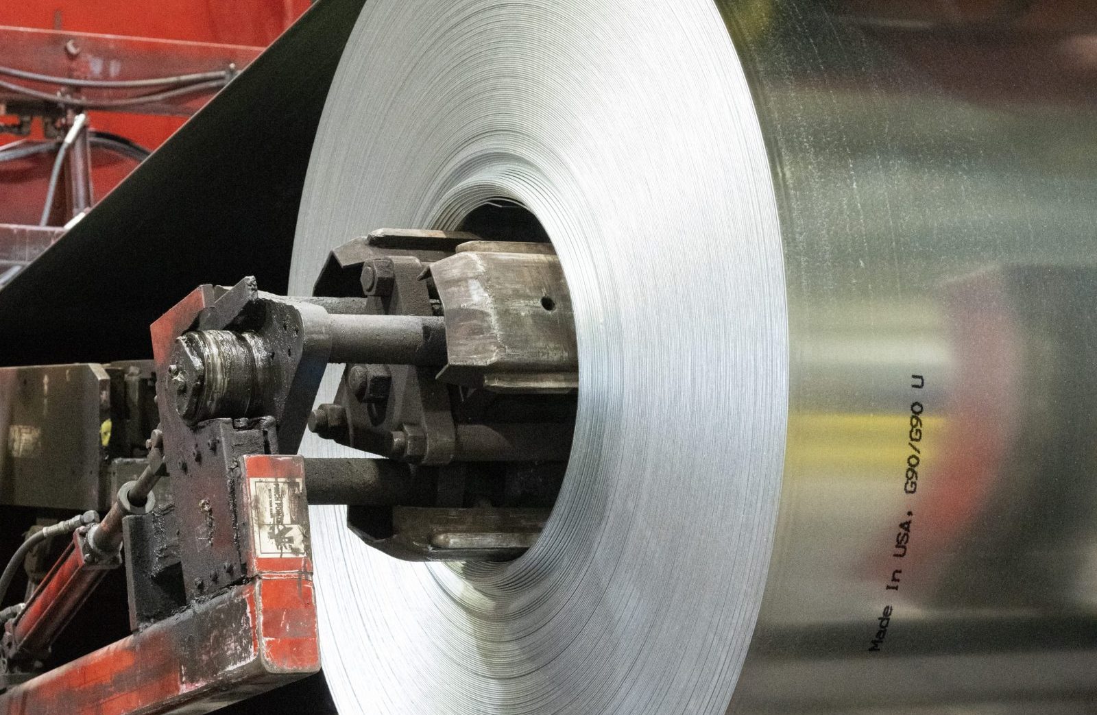 Close-up of a large coil of cold rolled steel being processed on industrial machinery, featuring a 'Made in USA' marking.
