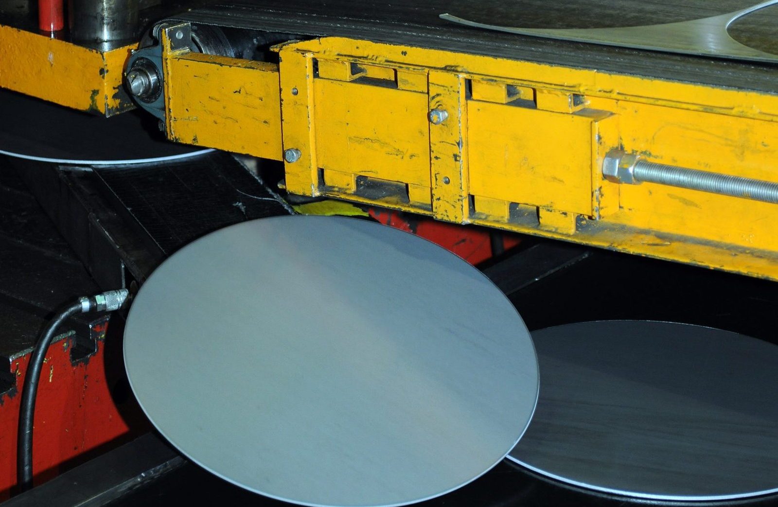 Close-up of steel blanks being cut into circular shapes on industrial machinery during the blanking process.
