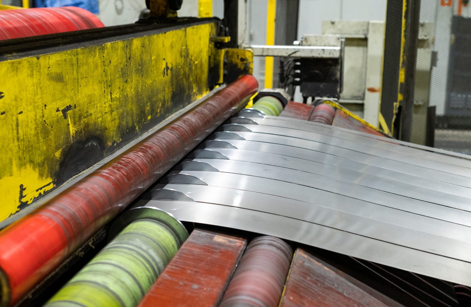 Close-up of steel strips being precisely slit into narrower widths on an industrial slitting machine.
