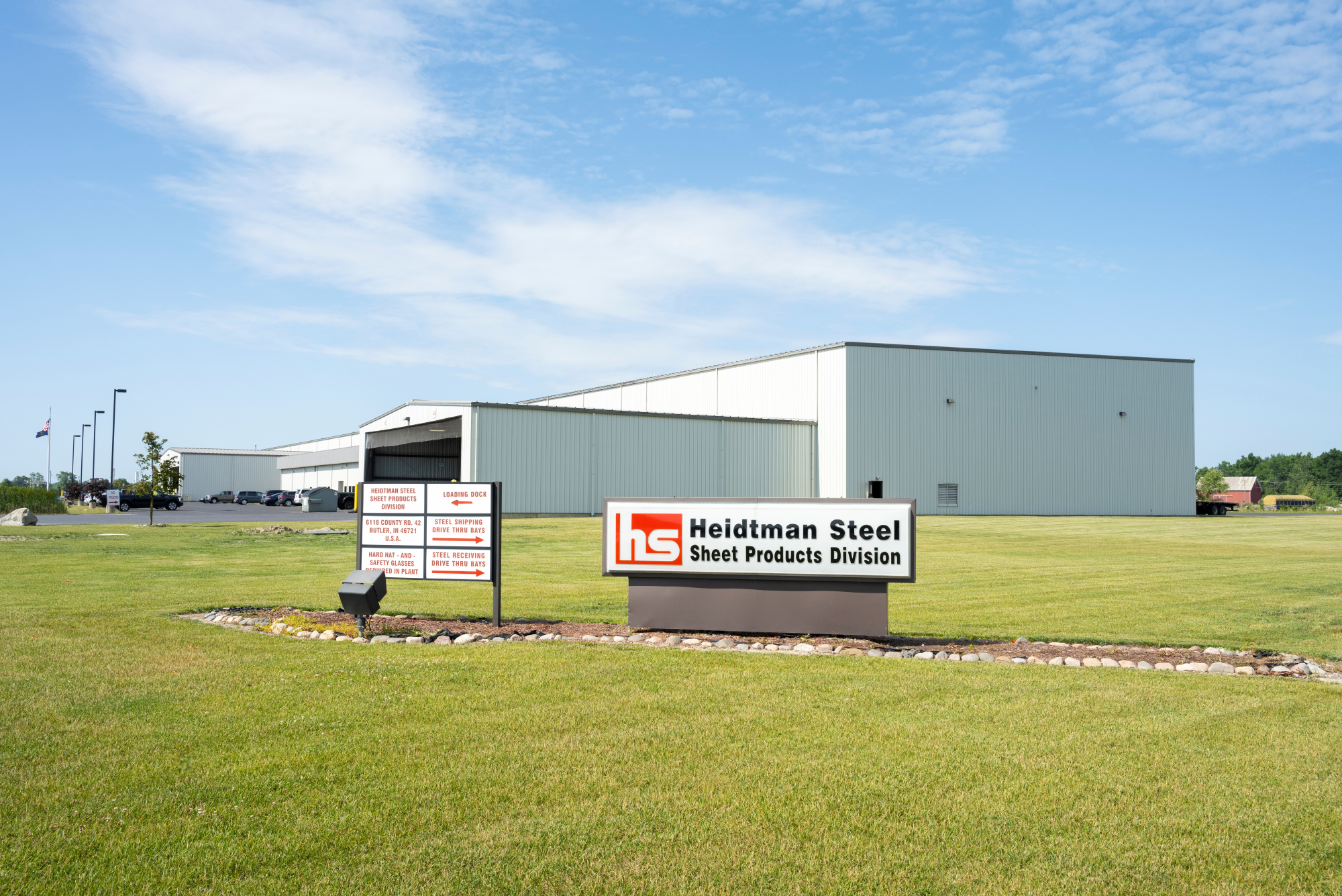 Exterior view of Heidtman Steel’s Butler, Indiana Sheet Products Division, featuring a large white industrial facility with company signage and a well-maintained landscape.
