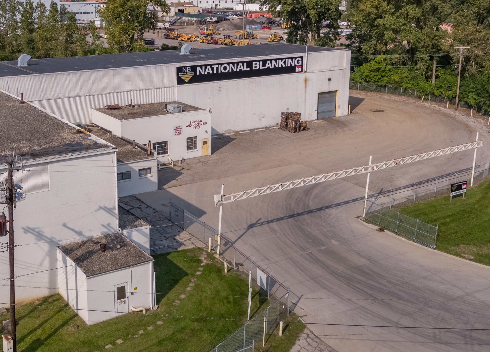 Aerial view of National Blanking facility with large white building, signage, and fenced parking lot.