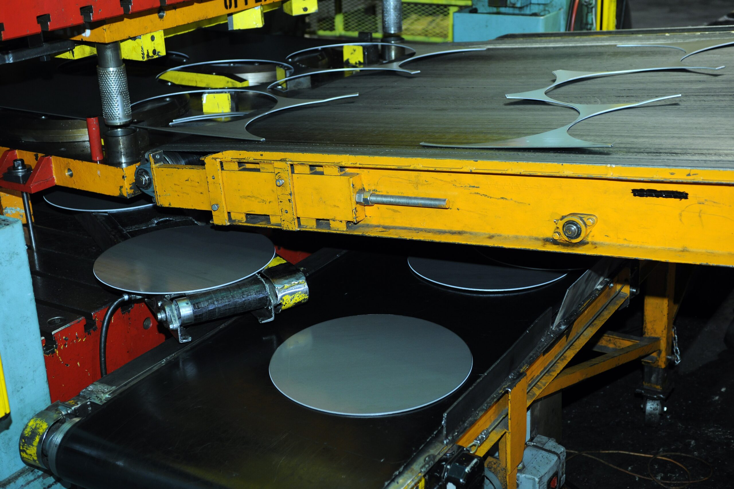 Blanking process machine cutting metal discs on a conveyor in a factory.